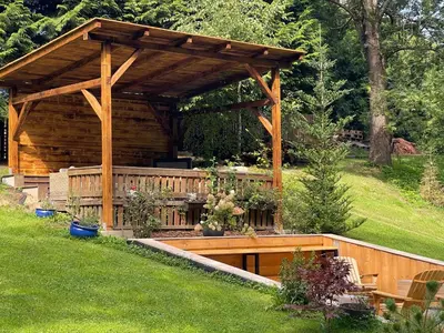 a wooden gazebo with a table in a yard at Penzion Kokorin Forest Villa in Konrádov