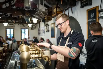 a man standing at a bar with a drink at Dobrý Kanec - Hostinec in Mělník