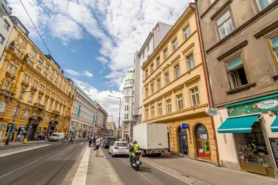 a busy city street with buildings and people on motorcycles at APT in center Prague by Michal&Friends in Prague