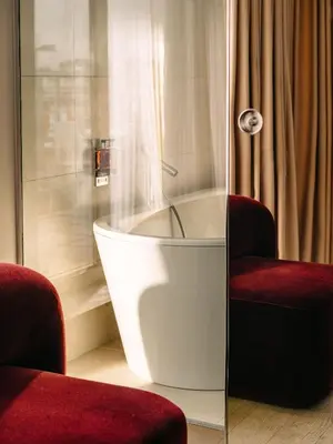 a bath tub in a room with two chairs at Hotel Josef in Prague