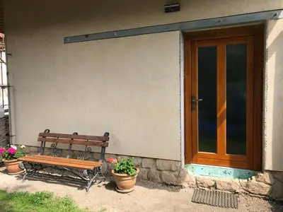 a wooden bench sitting outside of a house with potted plants at Apartmán U babičky in Prague