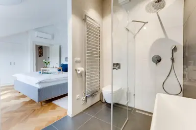 a bathroom with a shower and a bed in a room at Anděl design duplex, AC, garage in Prague