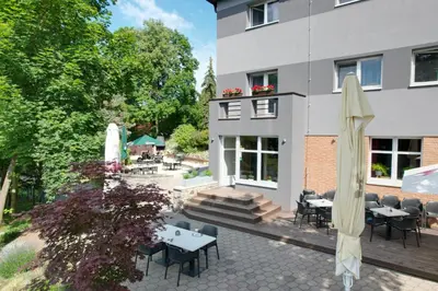 a patio with tables and umbrellas in front of a building at Penzion Harmony Javorník in Čtyřkoly