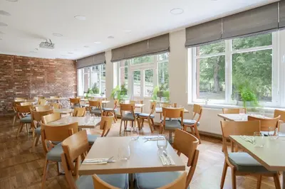 a dining room with tables and chairs and windows at Penzion Harmony Javorník in Čtyřkoly