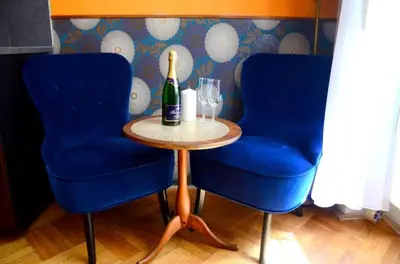 a table with a bottle of champagne and two blue chairs at ALLSTAR Vinohrady ateliers in Prague