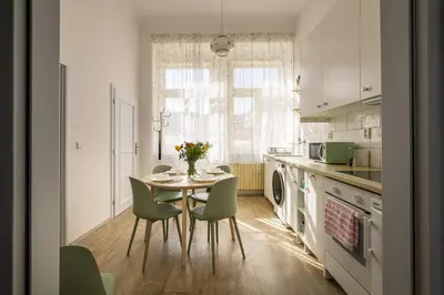 a kitchen with a table and chairs and a kitchen with a window at Wellness apartments Karlín in Prague