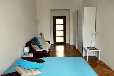 a bedroom with a blue bed and a couch at Wellness apartments Karlín in Prague