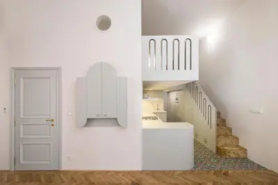 a white kitchen with a staircase and a white door at Downtown Designer apartment Karlin in Prague