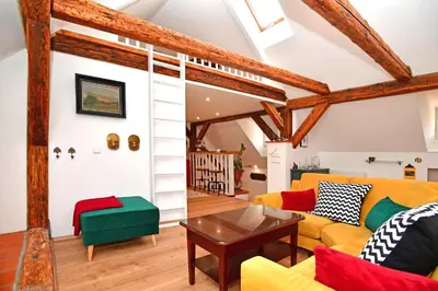 a living room with yellow and green furniture and wooden beams at Romantic apartment under the Prague castle in Prague