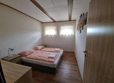 a small bedroom with a bed and two windows at Apartmány Vinařství Klučov in Lstiboř