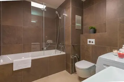 a bathroom with a tub and a toilet and a shower at Apartment Oscar with garage in Prague