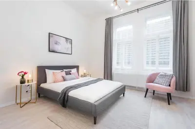 a bedroom with a bed and a pink chair at APTs in OLD TOWN PRAGUE by Michal&Friends in Prague