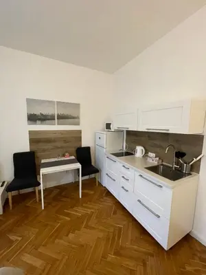 a kitchen with white cabinets and a sink and a table at Apartmen -Studio in Prague