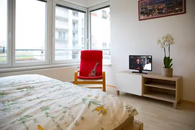 a bedroom with a bed and a red chair and a tv at Modern apartments - Airport 8mins in Prague
