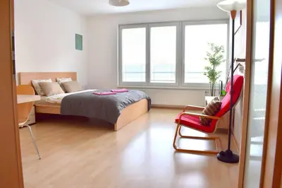 a bedroom with a bed and a red chair at Modern apartments - Airport 8mins in Prague