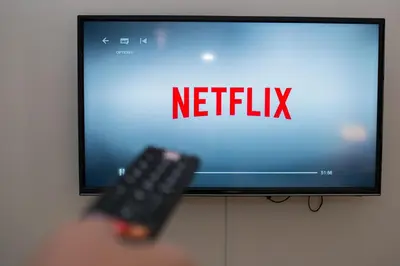 a person holding a remote control in front of a television at Apartment Florenc with 3-bathrooms & bedrooms in Prague