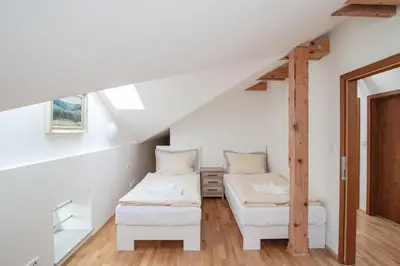 a attic room with two beds and a ladder at Pivovar Řevnice in Řevnice
