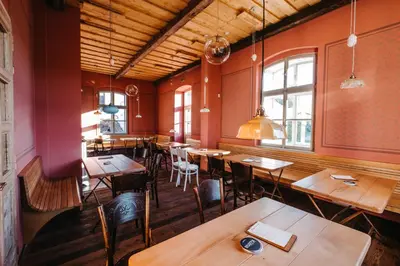 a restaurant with wooden tables and chairs and windows at Pivovar Řevnice in Řevnice