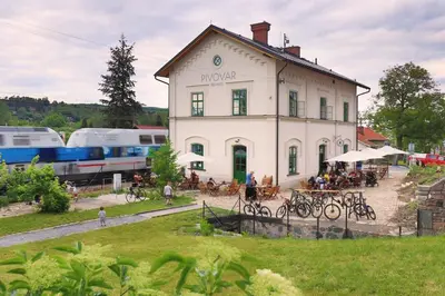 a white building with people sitting at tables in front of it at Pivovar Řevnice in Řevnice