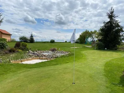 a putting green with a white umbrella on it at U Vrabčáka in Zlonín