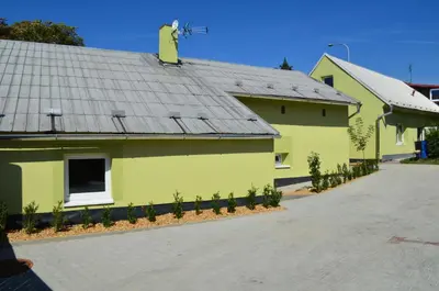 a yellow house with a metal roof and a driveway at Apartmány Kosmonosy, Hradištská 181 in Mladá Boleslav