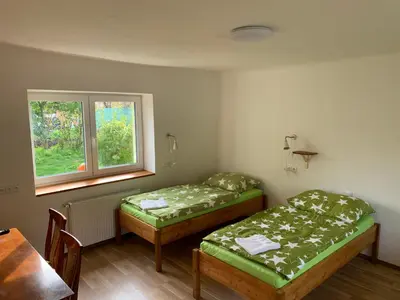two beds in a room with a table and a window at Apartmány Kosmonosy, Hradištská 193 in Mladá Boleslav