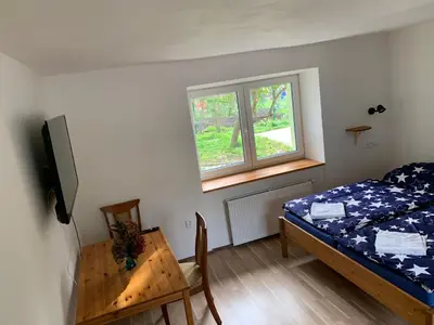 a bedroom with a bed and a window and a table at Apartmány Kosmonosy, Hradištská 193 in Mladá Boleslav