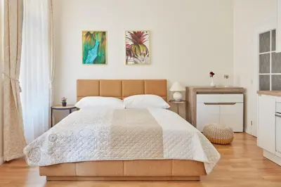 a bedroom with a large bed with two pictures on the wall at Prague Days - Sunlit Studio near National Museum in Prague