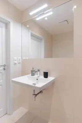 a white bathroom with a sink and a mirror at Prague Days - Sunlit Studio near National Museum in Prague