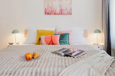 a bed with a book and fruit on it at Prague Days - Sunlit Studio near National Museum in Prague
