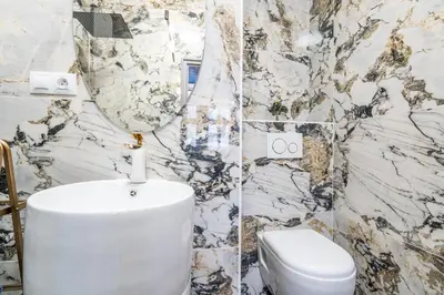 a bathroom with a white toilet and a marble wall at Charles Bridge Suite by Riverside in Prague