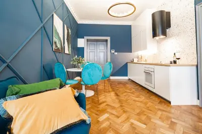 a blue living room with blue chairs and a kitchen at Charles Bridge Suite by Riverside in Prague