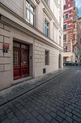 an empty street in front of a building with red doors at Charles Bridge Suite by Riverside in Prague