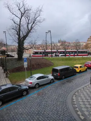 a group of cars parked on a street with a train at Emperor Castle View Suite in Prague