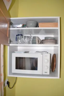 a white microwave on a shelf with dishes on it at Pension U akátu in Prague