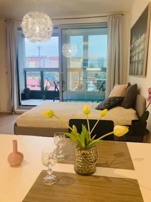 a living room with a bed and a table with flowers at Apartement Blanc Harfa design in Prague