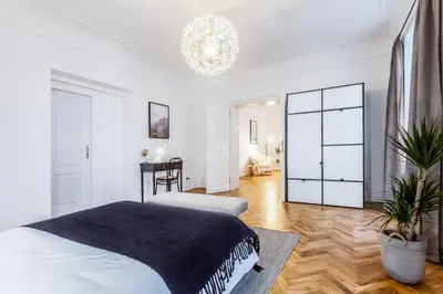 a white bedroom with a bed and a chandelier at Old Town 2 BDR apartment, free coffee in Prague