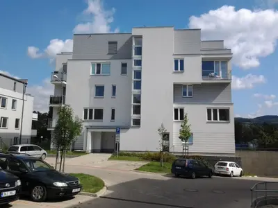a white building with cars parked in a parking lot at Apartmán Residence Nábřeží in Beroun