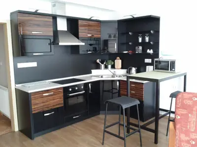 a kitchen with black cabinets and a kitchen island with a microwave at Apartmán Residence Nábřeží in Beroun