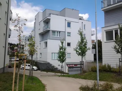 a white building with trees in front of it at Apartmán Residence Nábřeží in Beroun