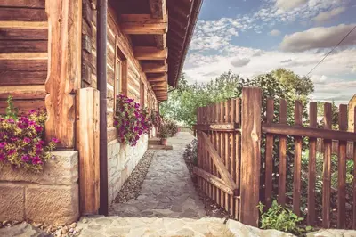 a wooden fence next to a house with flowers at Roubenka u Huvarů in Tachov