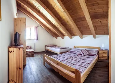 a bedroom with a large bed in a room with wooden ceilings at Roubenka u Huvarů in Tachov