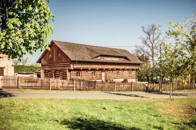 an old wooden building with a fence in front of it at Roubenka u Huvarů in Tachov