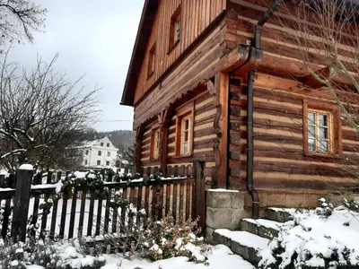 a wooden cabin in the snow with a fence at Roubenka u Huvarů in Tachov