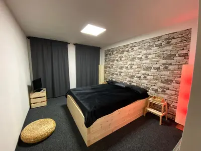 a bedroom with a bed and a brick wall at WELLNESS APARTMÁN KAROLÍNA in Milovice