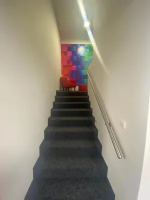 a staircase with a red chair and a colorful wall at WELLNESS APARTMÁN KAROLÍNA in Milovice