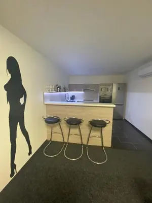 a woman standing in a kitchen with two stools at WELLNESS APARTMÁN KAROLÍNA in Milovice