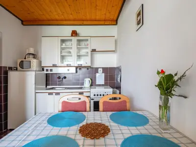 a kitchen with a table and two chairs and a kitchen with a refrigerator at Apartment Rabyně-1 by Interhome in Rabyně