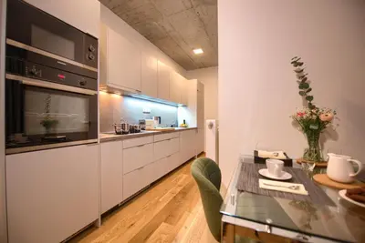 a kitchen with white cabinets and a glass table at Residence Soukenicka in Prague