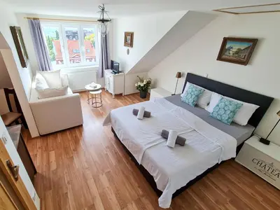 a bedroom with a large bed and a living room at Apartmán Praha Břevnov in Prague